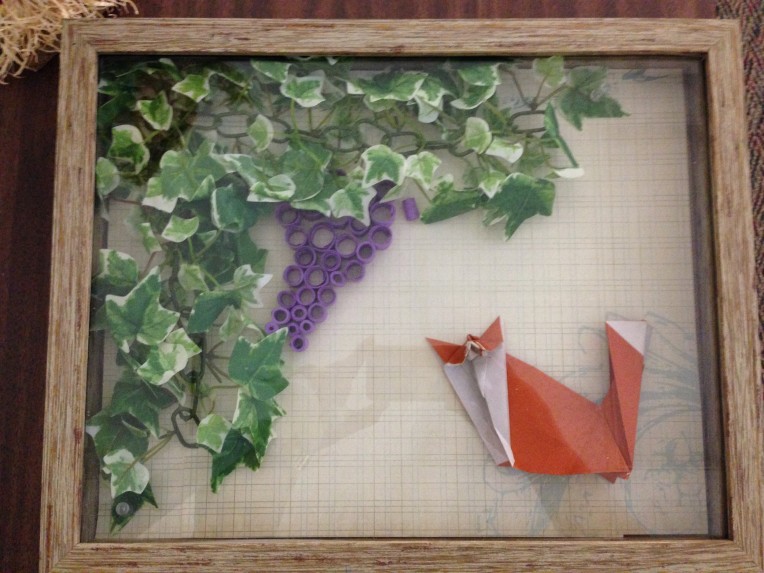 Origami fox, foliage, and grapes in a shadow box